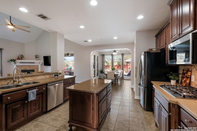 kitchen with stainless steel appliances, a center island, vaulted ceiling, sink, and dark brown cabinets