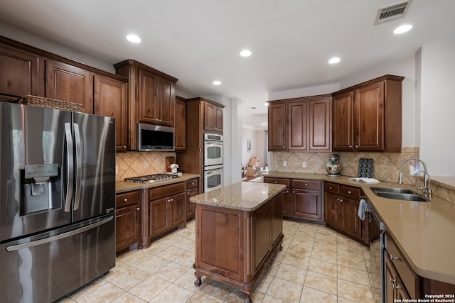 kitchen with a kitchen island, tasteful backsplash, sink, and stainless steel appliances