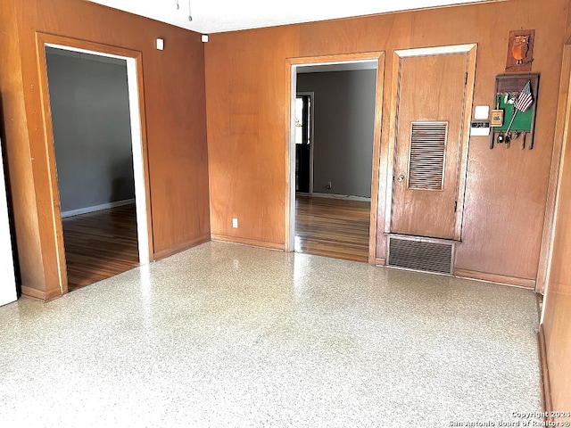 unfurnished room featuring wooden walls