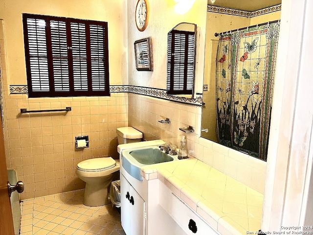 bathroom with toilet, vanity, tile patterned floors, and tile walls