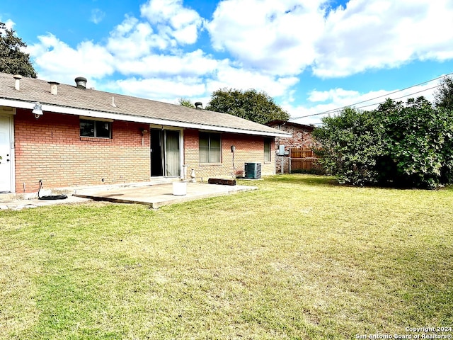 rear view of property with central AC, a patio, and a yard