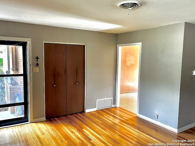 unfurnished bedroom with a textured ceiling, a closet, and light wood-type flooring