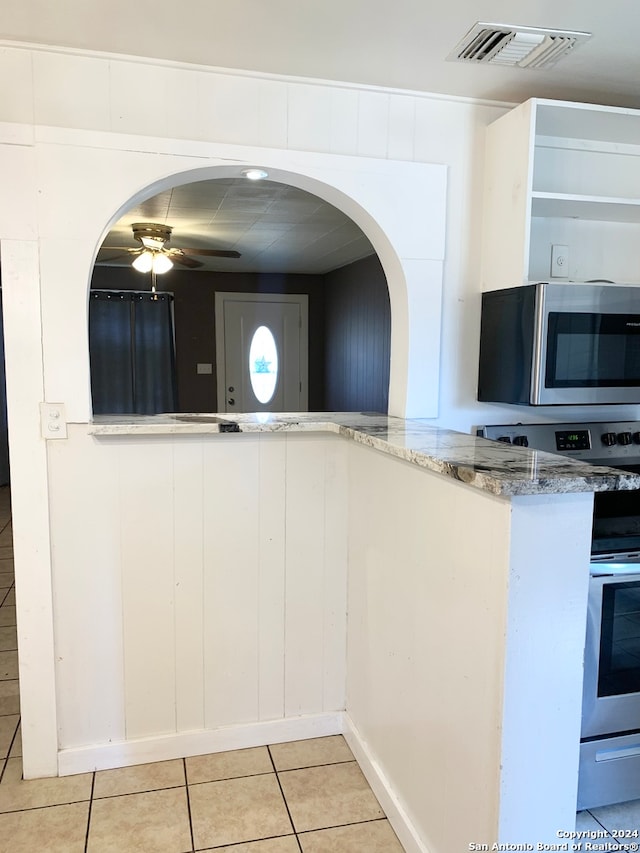 kitchen featuring white cabinets, light stone countertops, light tile patterned flooring, and white range