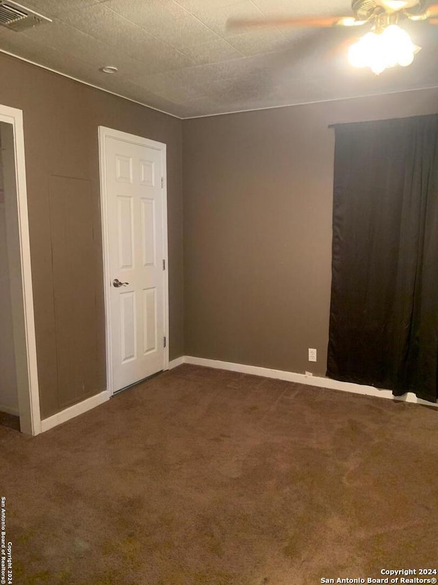 spare room featuring ceiling fan, a textured ceiling, and dark colored carpet