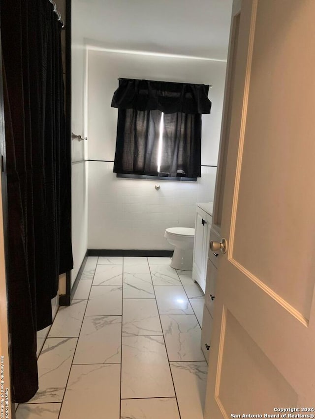 bathroom with vanity, toilet, and tile walls