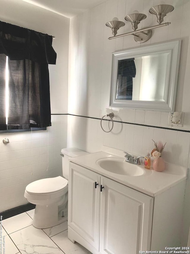 bathroom with vanity, toilet, and tile walls