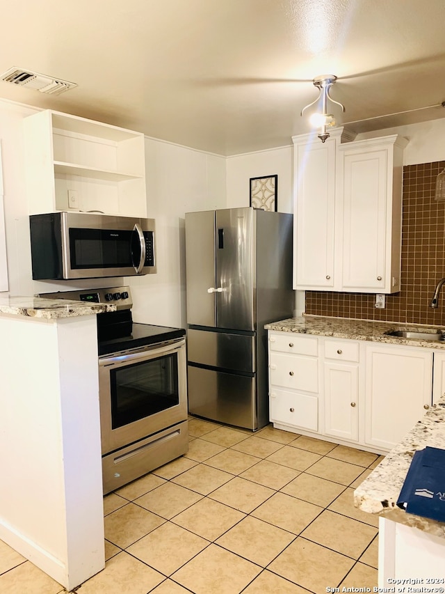 kitchen featuring white cabinets, sink, light tile patterned floors, backsplash, and stainless steel appliances