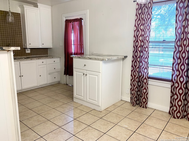 kitchen featuring backsplash, decorative light fixtures, stone counters, white cabinetry, and light tile patterned flooring