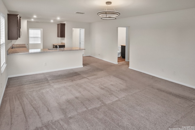 unfurnished living room with sink and light carpet