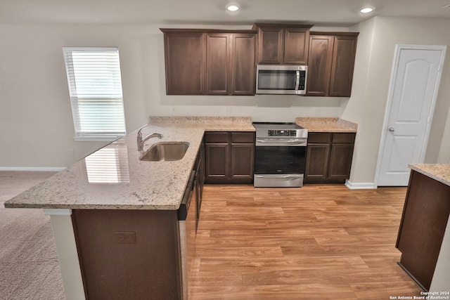 kitchen featuring light stone countertops, sink, stainless steel appliances, dark brown cabinets, and light wood-type flooring