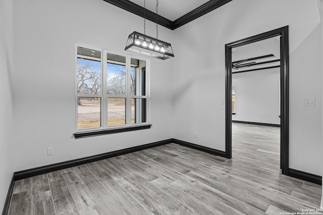 unfurnished dining area with crown molding and light wood-type flooring