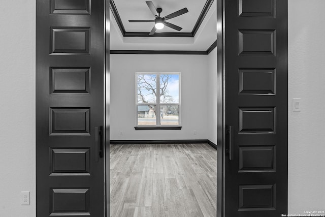 foyer with crown molding, ceiling fan, a tray ceiling, and light hardwood / wood-style floors