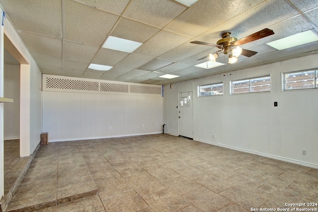 empty room with ceiling fan and a drop ceiling