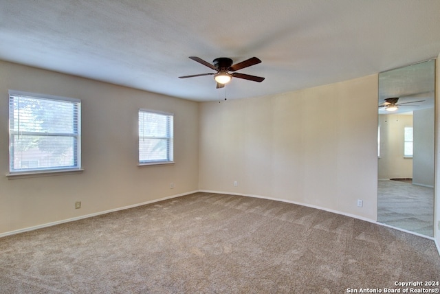 spare room featuring ceiling fan, light colored carpet, and a textured ceiling