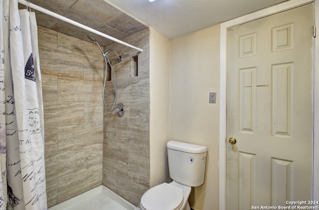 bathroom with a textured ceiling, toilet, and curtained shower