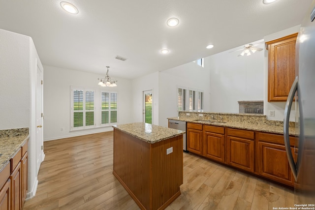 kitchen featuring decorative light fixtures, stainless steel appliances, light hardwood / wood-style floors, and sink