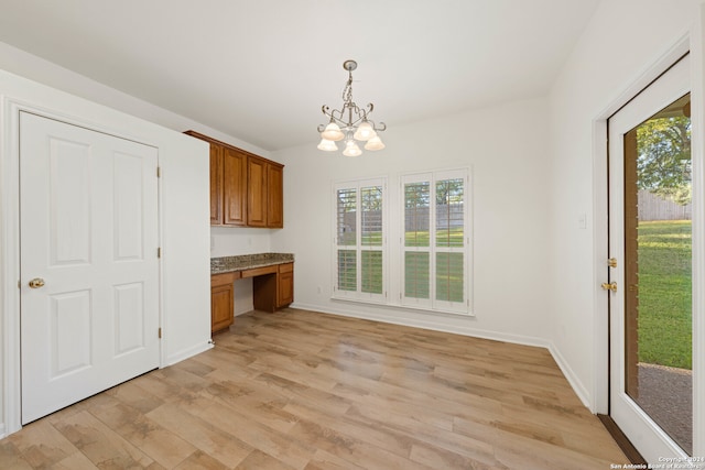 kitchen with light wood-type flooring, built in desk, plenty of natural light, and hanging light fixtures