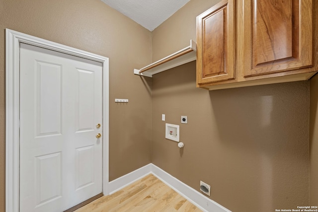 washroom featuring hookup for an electric dryer, hookup for a washing machine, light wood-type flooring, cabinets, and a textured ceiling