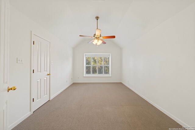 empty room featuring ceiling fan, lofted ceiling, and carpet flooring