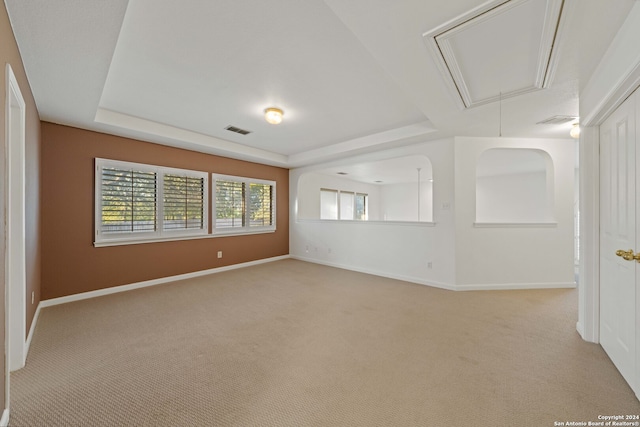 carpeted spare room featuring a tray ceiling