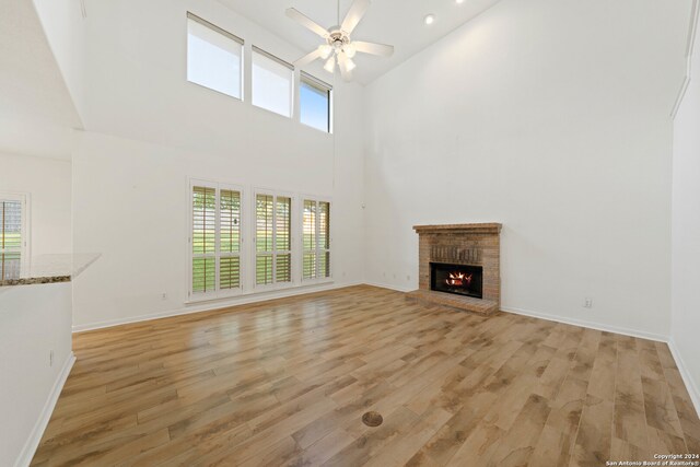 unfurnished living room with a high ceiling, a brick fireplace, and a healthy amount of sunlight