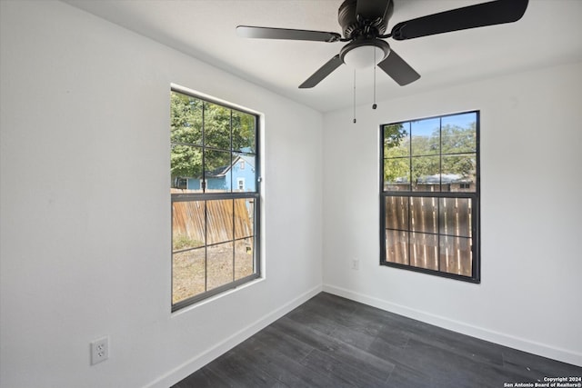 unfurnished room featuring ceiling fan, dark wood-type flooring, and a healthy amount of sunlight