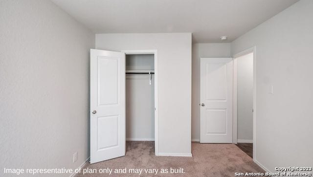 unfurnished bedroom featuring light carpet and a closet