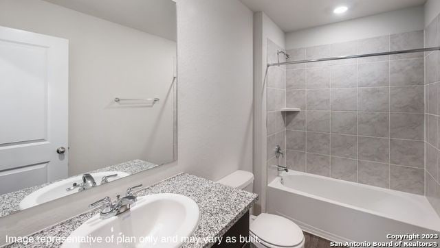 full bathroom with vanity, tiled shower / bath combo, and toilet