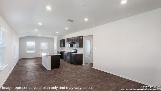 kitchen featuring stainless steel range, dark brown cabinets, dark wood-type flooring, a center island with sink, and lofted ceiling