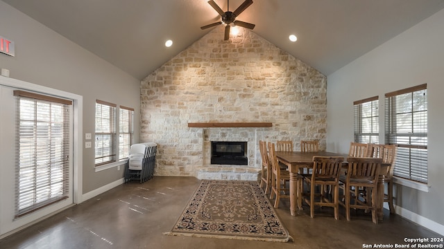 dining room featuring high vaulted ceiling, ceiling fan, and a stone fireplace