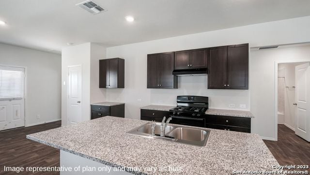 kitchen featuring gas stove, sink, an island with sink, and dark hardwood / wood-style floors