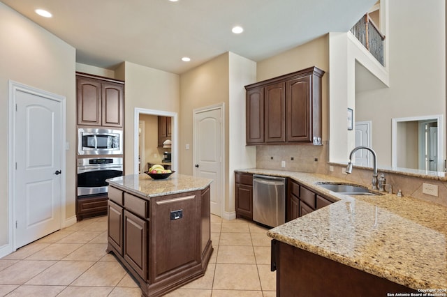 kitchen featuring light stone countertops, sink, kitchen peninsula, dark brown cabinets, and appliances with stainless steel finishes