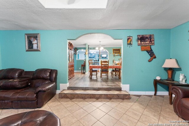 22620 Little Walnut Dr, San Antonio, TX 78264 - living area featuring light tile patterned flooring, arched walkways, a textured ceiling, and baseboards