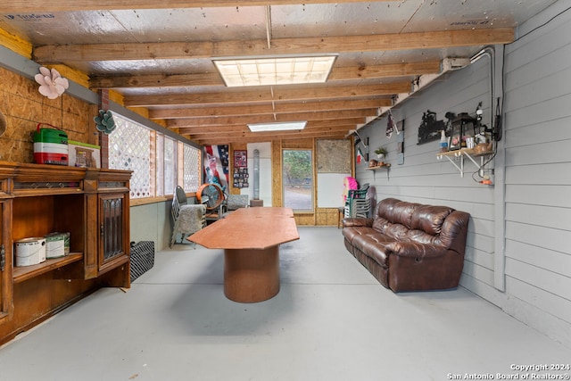 recreation room featuring concrete flooring, vaulted ceiling, and wood walls