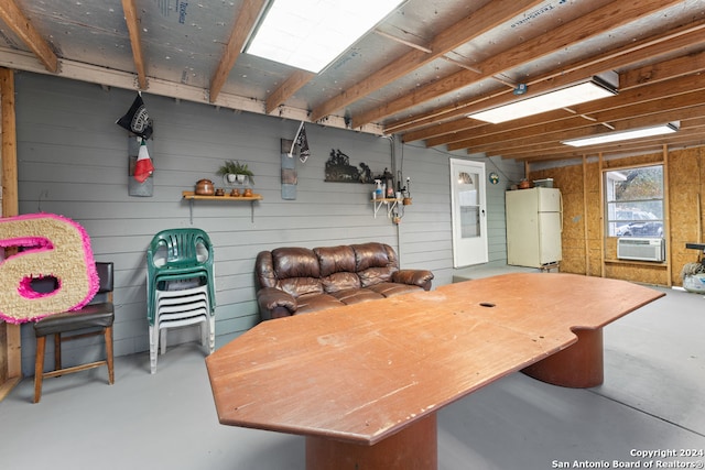 basement featuring cooling unit and white fridge