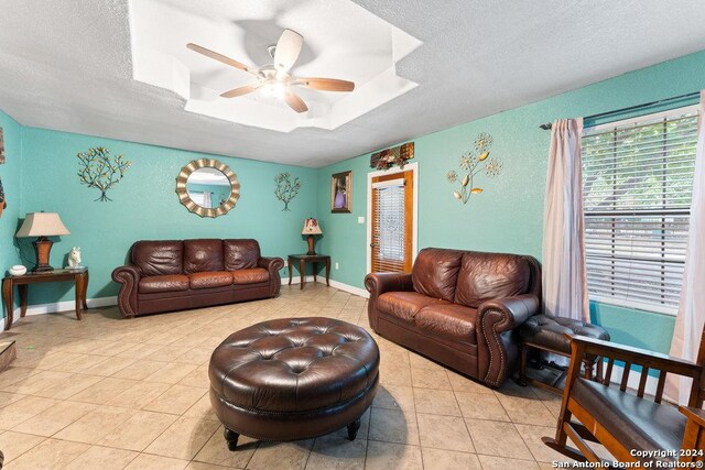 22620 Little Walnut Dr, San Antonio, TX 78264 - living area with a ceiling fan, tile patterned flooring, a tray ceiling, a textured ceiling, and baseboards