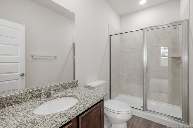 bathroom featuring vanity, toilet, walk in shower, and hardwood / wood-style flooring