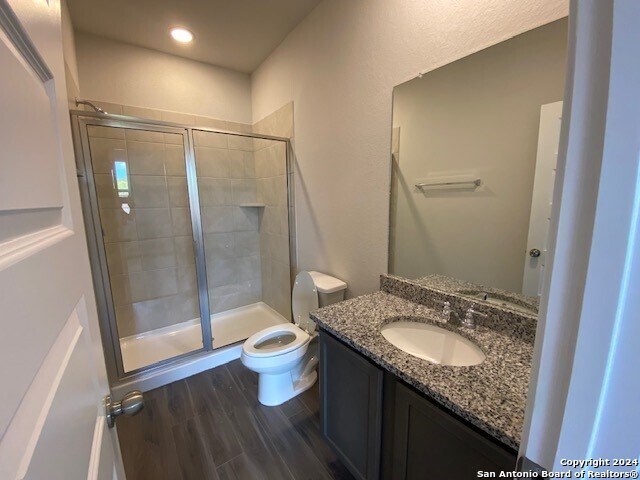 bathroom featuring hardwood / wood-style floors, vanity, an enclosed shower, and toilet