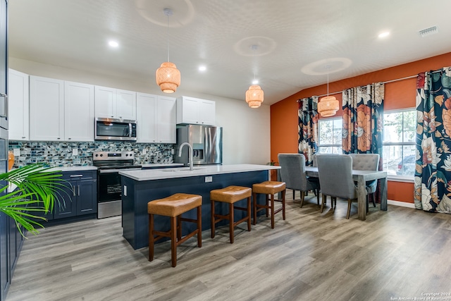 kitchen featuring a kitchen breakfast bar, hanging light fixtures, a kitchen island with sink, light hardwood / wood-style floors, and stainless steel appliances