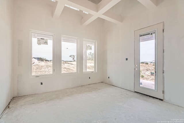 unfurnished room featuring coffered ceiling, a wealth of natural light, and beam ceiling