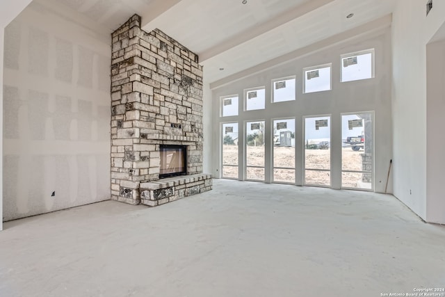 unfurnished living room featuring a fireplace, concrete floors, high vaulted ceiling, and beamed ceiling