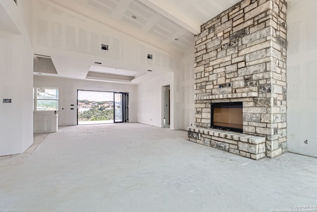 unfurnished living room featuring beam ceiling, a stone fireplace, and high vaulted ceiling