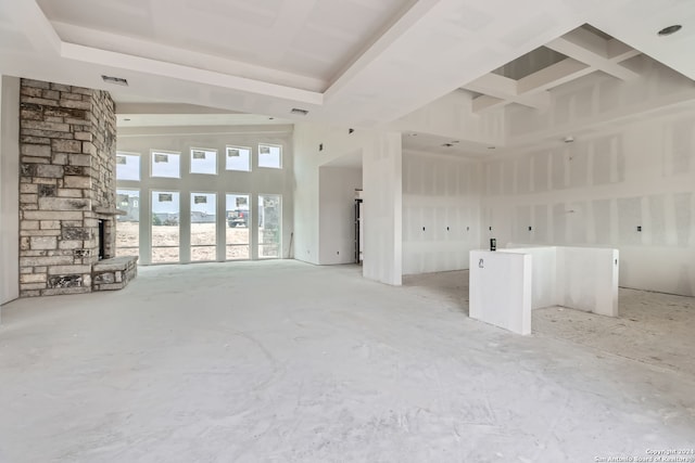 unfurnished living room featuring a high ceiling and a wood stove