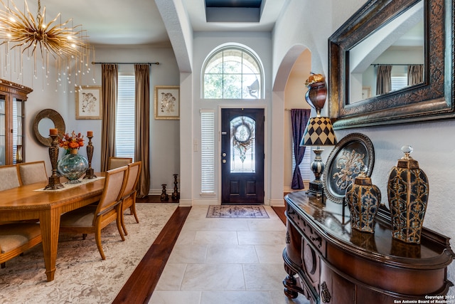 tiled entrance foyer with a notable chandelier