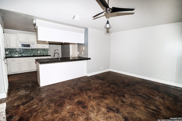 kitchen with white cabinetry, sink, ceiling fan, kitchen peninsula, and decorative backsplash