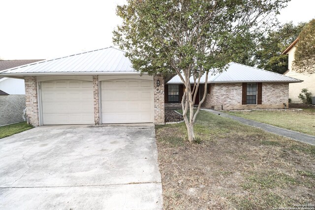 7227 Trace Buckle, San Antonio, TX 78240 - view of front facade with driveway, metal roof, an attached garage, and brick siding