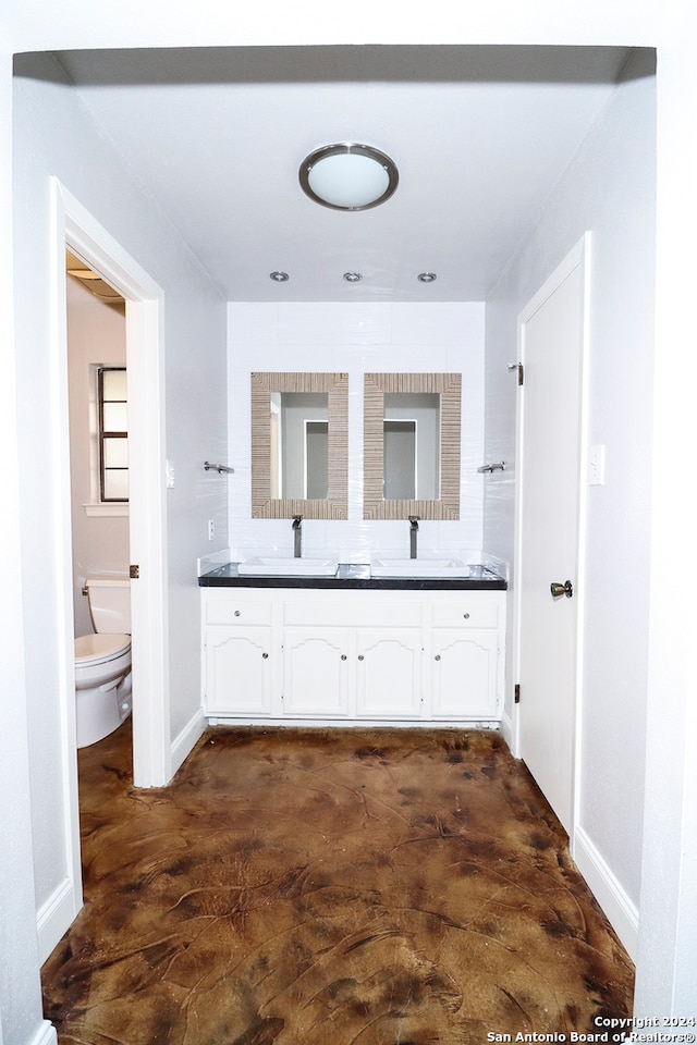 bathroom featuring vanity, toilet, and concrete flooring