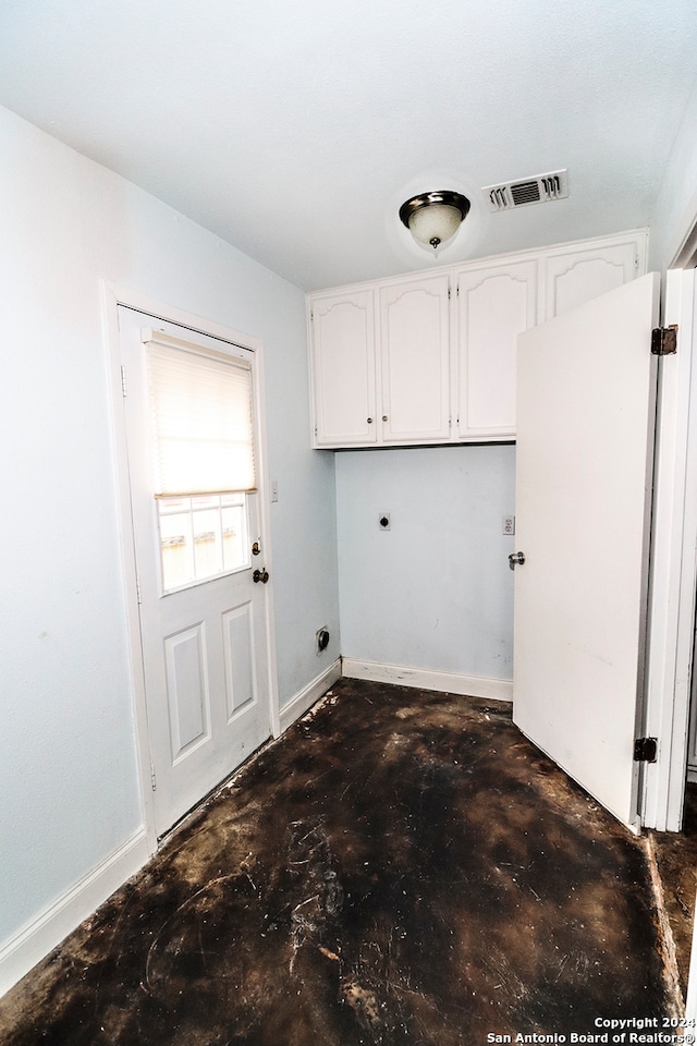 clothes washing area featuring electric dryer hookup and cabinets