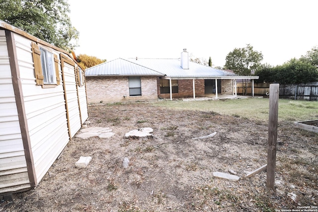 7227 Trace Buckle, San Antonio, TX 78240 - back of house featuring fence, metal roof, a chimney, brick siding, and a patio