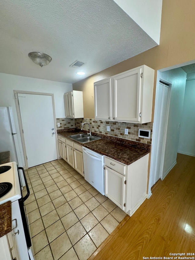 kitchen with white cabinetry, sink, backsplash, light hardwood / wood-style floors, and white appliances